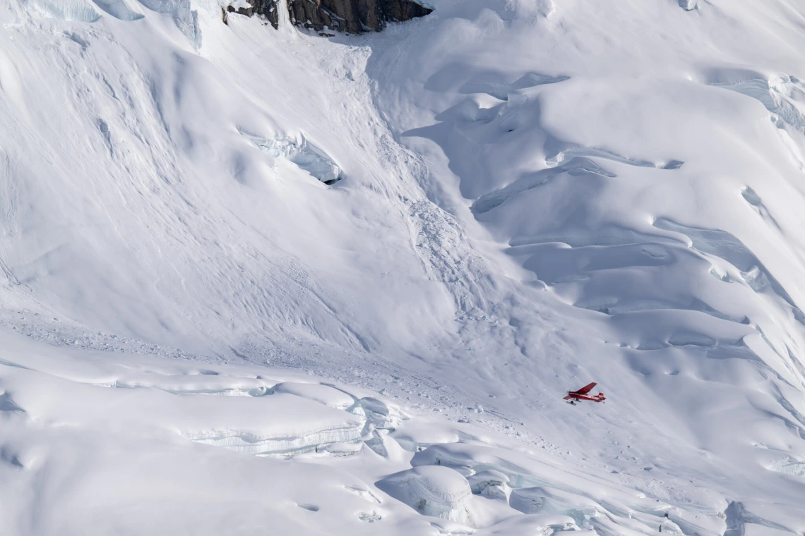 A bush plane began to climb after taking off from a snow-covered glacier.